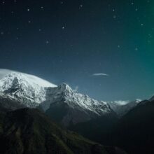 Fotobehang - Northern Lights - Snowy Mountain Landscape in Winter Night with Cosmos in the Background